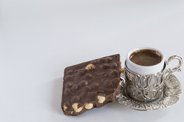Turkish coffee in the copper cup and healthy hazelnut chocolate on the white background for cafe or shop concept. 