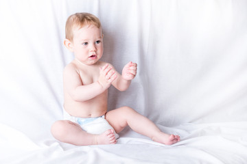 Cute blue-eyed baby 6-9 months smiling and playing on white background. Children's emotions and...