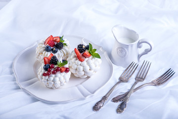 Delicate white meringues with fresh berries on the plate. Dessert Pavlova. Wedding cake.