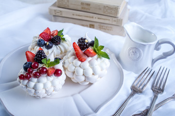 Delicate white meringues with fresh berries on the plate. Dessert Pavlova. Wedding cake.