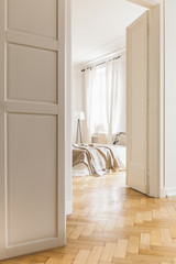 White wall with molding in spacious loft interior with bedroom and wooden floor. Real photo