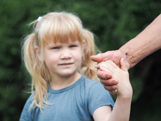 The child holds the hand of an adult