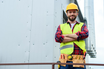 male professional engineer with tool belt posing with crossed arms