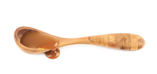 Wooden spoon of caramel sauce isolated