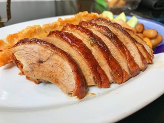 roasted duck in Chinese style with fried crispy pork on dish in restaurant