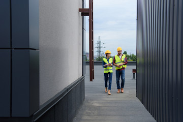 architects in helmets with blueprint and coffee walking on roof