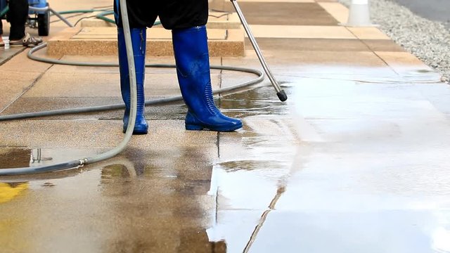Outdoor floor cleaning with high pressure water jet. Focus on worker