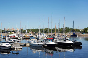Fototapeta na wymiar Modern yacht club with various motor and sail boats moored to pier floating on water in summer