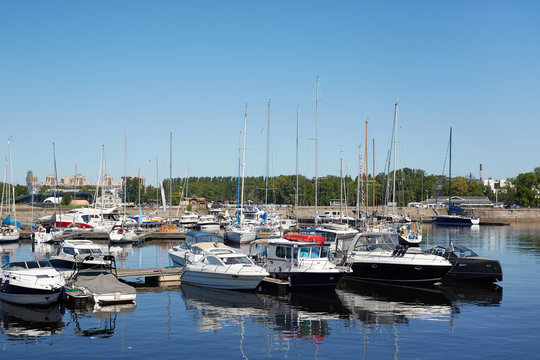 Modern yacht club with various motor and sail boats moored to pier floating on water in summer
