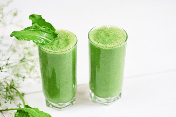 Blended green smoothie with ingredients or cocktail on white background, breakfast vegan with a place for your text, concept of raw food