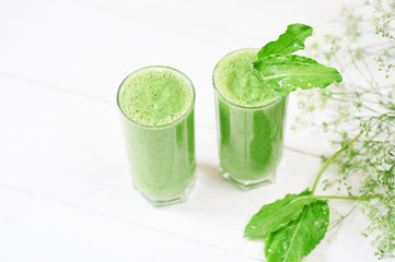 Blended green smoothie with ingredients or cocktail on white background, breakfast vegan with a place for your text, concept of raw food