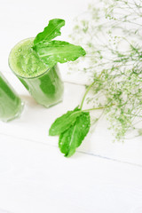 Blended green smoothie with ingredients or cocktail on white background, breakfast vegan with a place for your text, concept of raw food