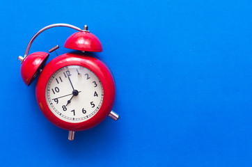 Red alarm clock isolated on blue background with copy space.