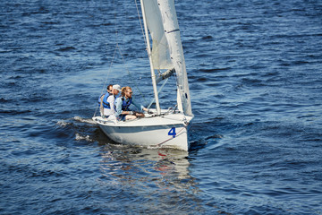 Group of men sitting on sailboat deck and sailing with professional while floating on river