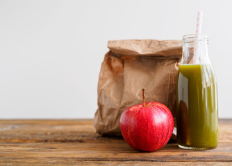 Grüner Smoothie, ein roter Apfel und eine Papiertüte