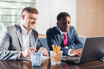 Portrait of two business partners sitting at a table together and working.