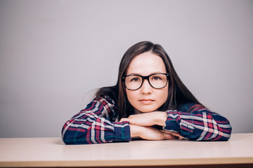 Close-up portrait of a beautiful charming woman with glasses on a gray background