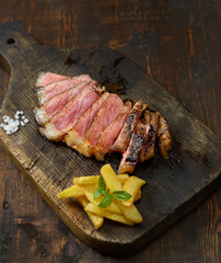 grilled steak on a cutting board on a wooden background.