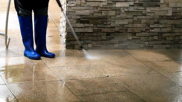 Outdoor floor cleaning with high pressure water jet. Focus on worker