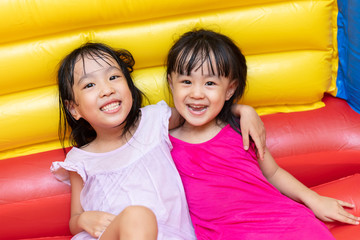 Asian Little Chinese sisters playing at inflatable castle