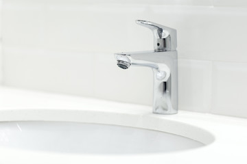 chrome crane on the ceramic wash basin in the bathroom close up