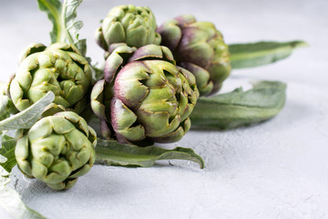 Obraz premium Fresh raw artichokes on grey background. Ripe organic artichoke flower with copy space