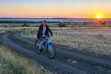 Fototapeta na wymiar man ride a bike in the country on the field in the evening