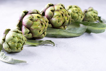Obraz premium Fresh raw artichokes on grey background. Ripe organic artichoke flower with copy space