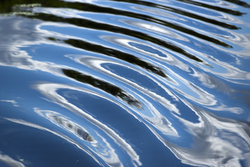 Wave texture on the river with reflecting clouds in the water surface.