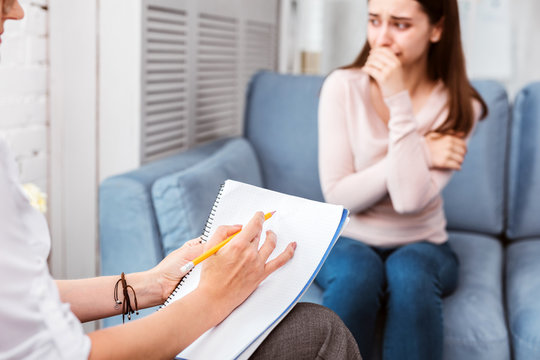 General practitioner. Unhappy young woman feeling sad and visiting a therapist while suffering from constant headaches