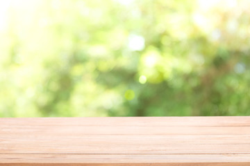 Blank wood table top with sun and blur green tree.