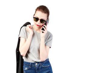 Carelessly dressed European girls standing on a white background, talking on the smartphone and smiling pleasantly while communicating with friends.