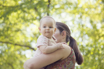 the child sits in the hands of his mother on a Sunny day