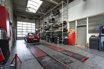 Red car in a workshop with tires. Professional vehicle repair