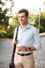 Happy young man in shirt carrying bag walking