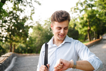 Fototapeta premium Smiling young man in shirt walking at the city park