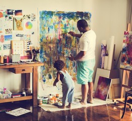 Black artist dad doing his art work with his child 
