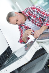 Man using screwdriver on photocopier