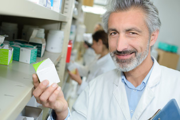 friendly male pharmacist dispensing medicine holding a box of tablets