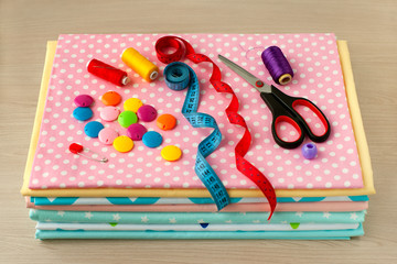 A pile of cotton fabric for sewing clothes and bed linen. A lot of colorful cotton fabric, centimeter tape, scissors, thread for sewing clothes and bed linen. Cotton for tailoring.
