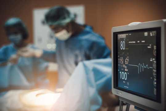 Electrocardiogram In Hospital Surgery Operating  Emergency Room Showing Patient Heart Rate With Blur Team Of Surgeons Background   