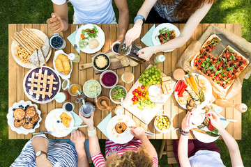Top view of a wooden table with pizza, cherry pie, fruit, vegetables and pancakes during a...