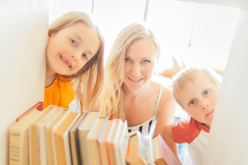 Photo of mother with son and daughter peeping out of shelter with books