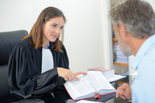 Lawyer showing text from book to client