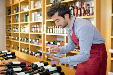 winemaker in cellar controlling wine market prices on tablet