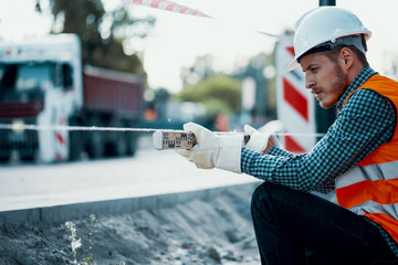 Worker measuring land with a leveling rod at a construction site