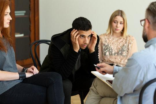 Depressed young man talking to his therapist about alcohol addiction during an AA meeting