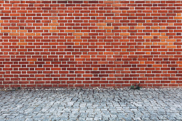 Retro red brick wall and cobblestone pavement.