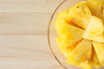 Pineapple on a plate placed on a wooden table.