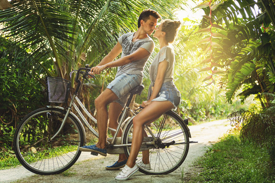 Young couple is riding a vintage bicycle on the country road in tropical country